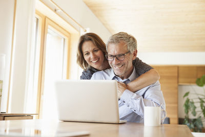 Happy mature couple sharing laptop at home