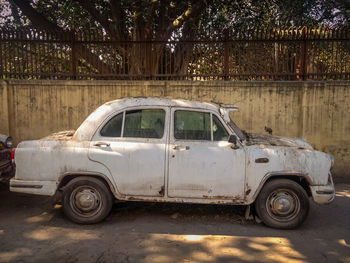 Abandoned car parked on road in city