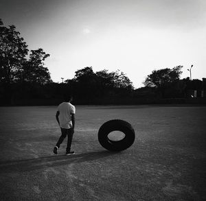 Rear view of man playing with ball on field against sky