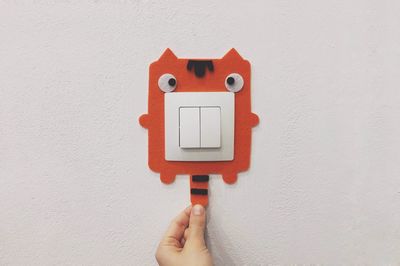 Close-up of hand holding red light against white wall