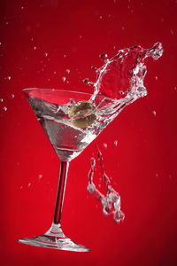 Close-up of cocktail splashing over red background