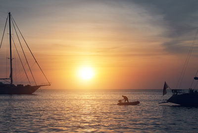 Man in silhouette boat on mediterranean sea against sky during sunset