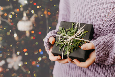 Female hands holding gift box. woman wearing violet sweater. faceless. christmas and new year