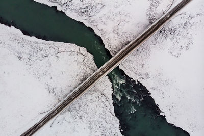 Directly above shot of bridge over river on snowcapped mountain