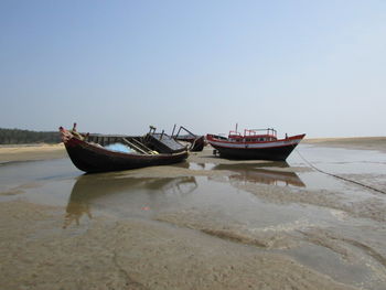 Boat moored on beach against clear sky