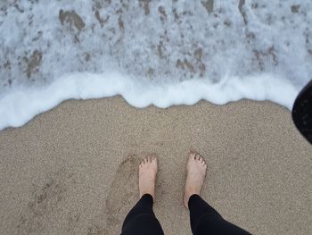 Low section of woman standing on sand at beach