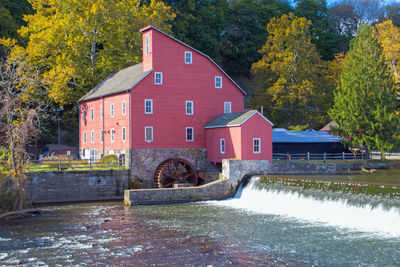 Built structure by river against trees and building