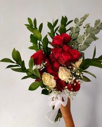 Close-up of person holding rose bouquet in vase