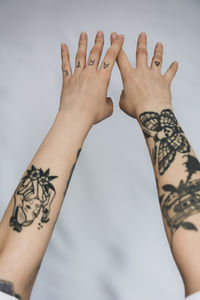 Low section of woman with tattoo on arms against gray background