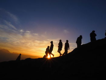 Silhouette people against sky during sunset