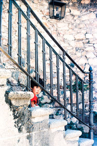 Portrait of cute kid sitting on staircase against stone wall