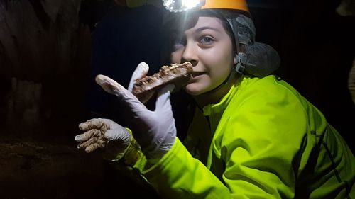 Teenage girl in protective clothing girl holding stone at night