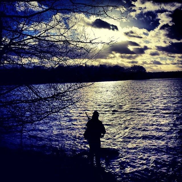 silhouette, water, sky, leisure activity, tranquility, lifestyles, sunset, tranquil scene, lake, standing, tree, beauty in nature, bare tree, scenics, men, nature, cloud - sky, outline