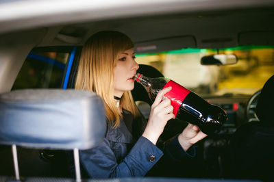 Woman having drink while sitting in car
