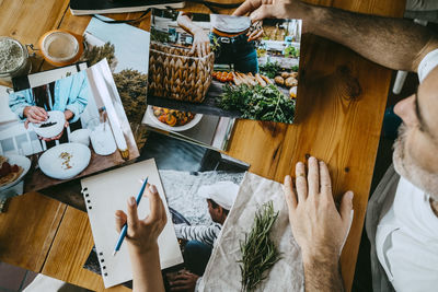 Directly above shot of food stylists reviewing photographs at table