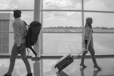 Rear view of man standing at airport against sky