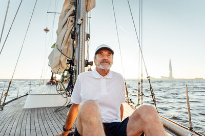 Man sitting on sailboat in sea against sky