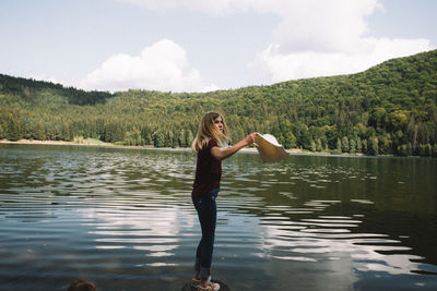 Side view full length of young woman standing by lake
