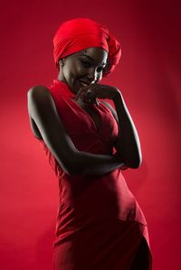 Young woman wearing dress standing against red background