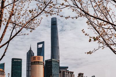 Low angle view of skyscrapers against cloudy sky