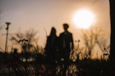 Silhouette people on field against sky during sunset