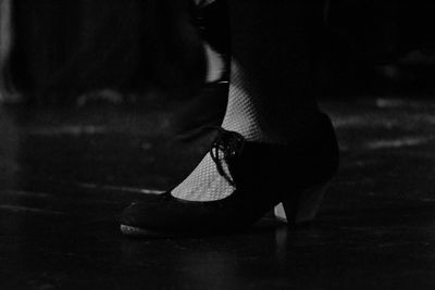 Low section of woman in high heels on wooden floor