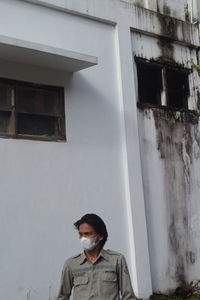 Portrait of young man standing against building