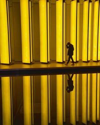 Side view of silhouette man standing against yellow wall