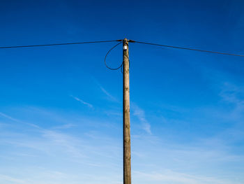 Low angle view of electricity pylon against blue sky