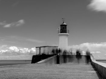 Lighthouse by sea against sky