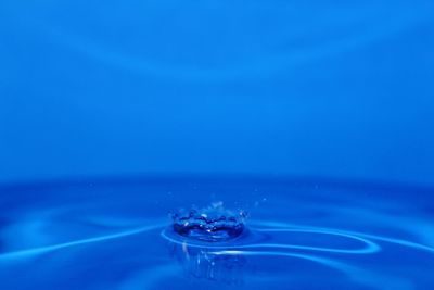Close-up of drop falling on blue water