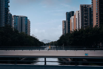 Bridge over canal by buildings against sky