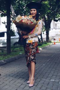 Portrait of woman standing on footpath in city