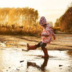 Rear view of boy walking in water against sky