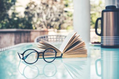 Close-up of eyeglasses and open book on table at yard