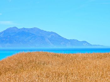 Scenic view of sea and mountains against blue sky