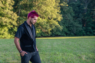 Man with dyed hair standing on grass land in park