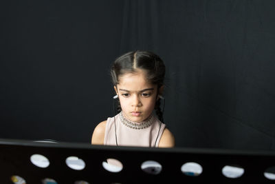 Girl wearing hearing aid while reading against wall