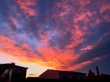 Silhouette houses against sky during sunset