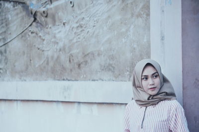 Woman wearing hijab while standing by wall
