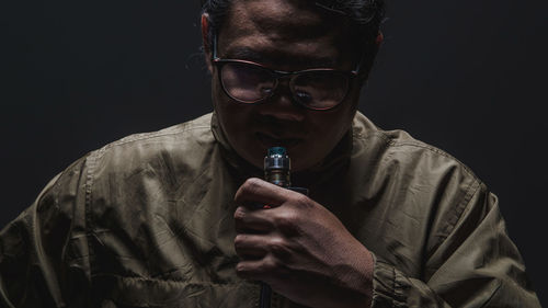 Portrait of young man wearing eyeglasses against black background