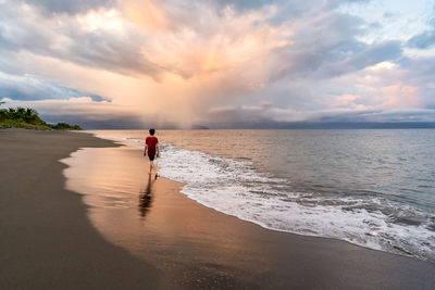 Teenager walking on beautiful beach at sunset