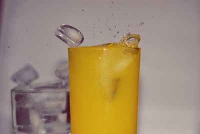 Close-up of ice cubes falling in orange juice at home