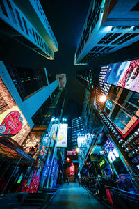 Low angle view of illuminated street amidst buildings at night