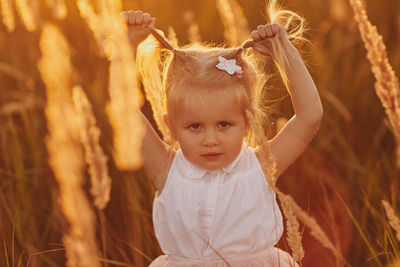 Portrait of cute girl with arms raised on field