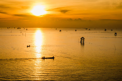 Fishing boat for small fish in the sea with sunset background, silhouette concept.