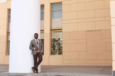 Man in suit standing against building