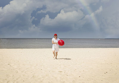 Full length of woman standing on beach against sky
