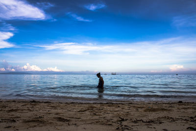 Man standing in sea against sky