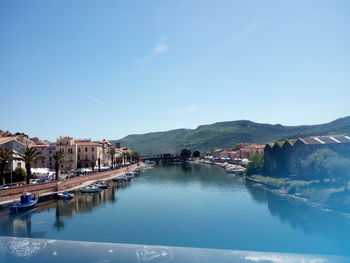 Scenic view of river by buildings against blue sky